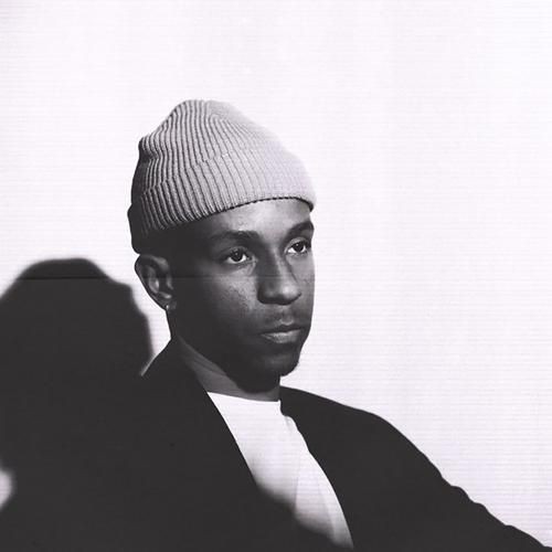 Black and white portrait of a person wearing a beanie, gazing thoughtfully to the side.